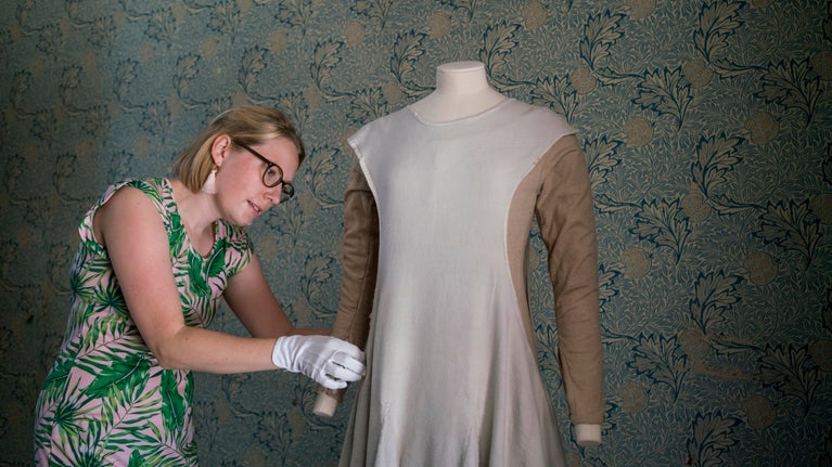 A curator dressing a mannequin in Victorian clothes at Red House, London